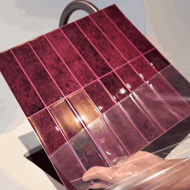 Peeling the backing off an Ebba sheet, pressing it onto the wall, then rinsing it under running water
